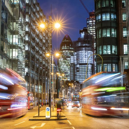 London city view traffic at night - Busy road in central London with red bus and traffic and modern buildings all around - Blurred bus due to long exposure, time and speed concepts